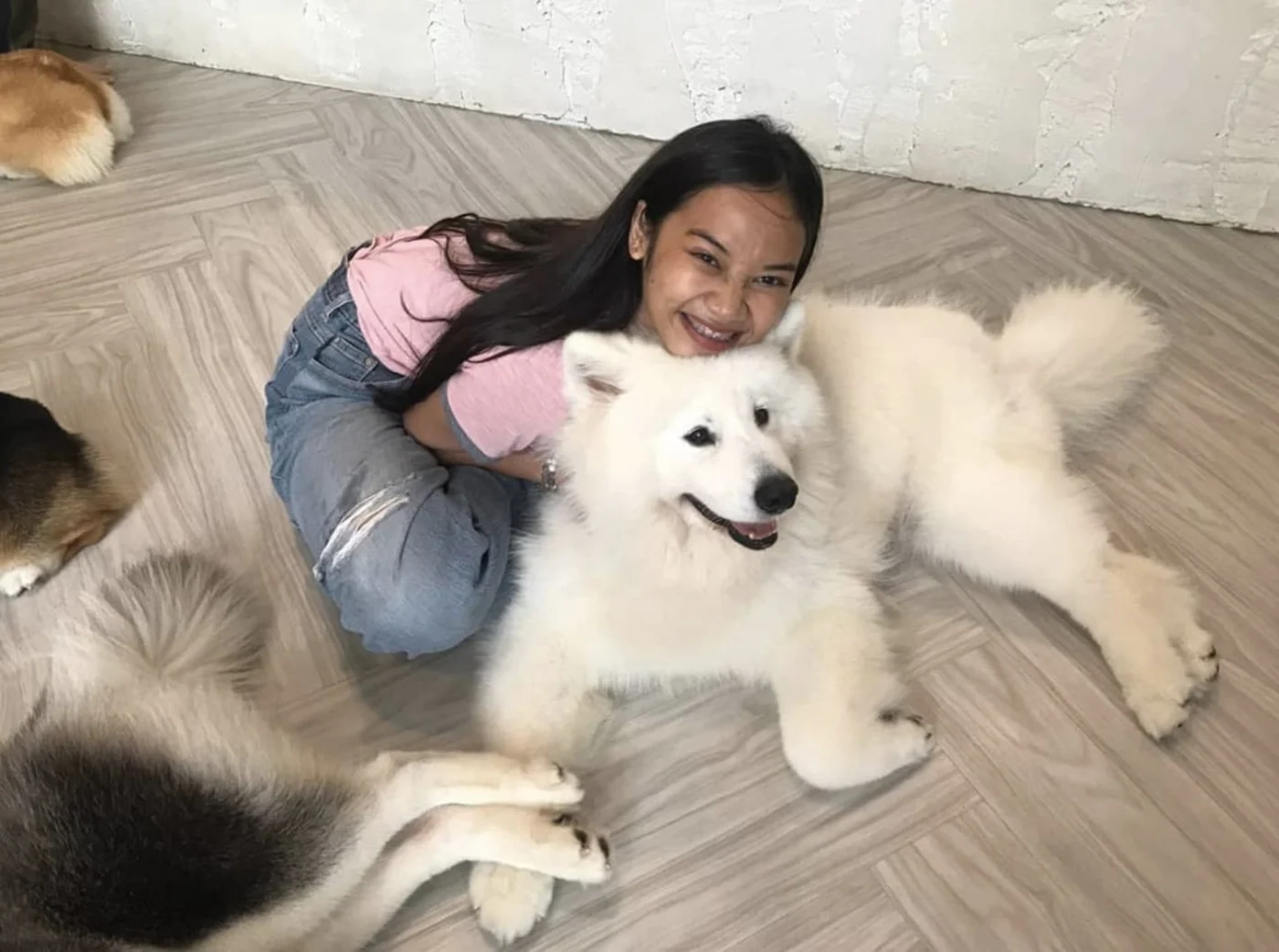 Nina smiling while cuddling a fluffy white dog